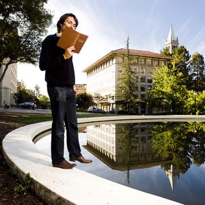 Student reading a book on the edge of the Hearst Mining reflection pool