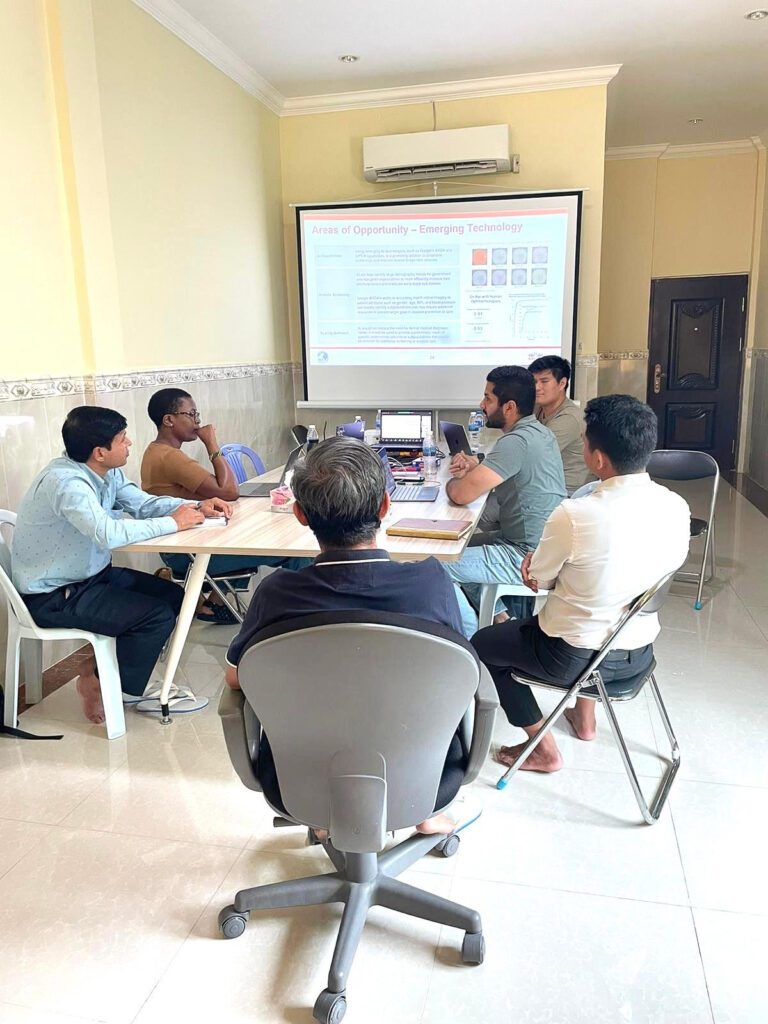 A group of people around a table looking at a screen presentation