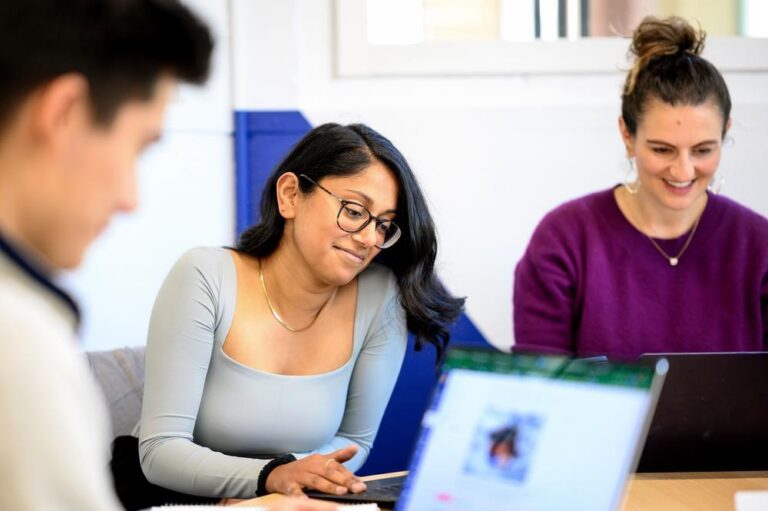 A man and two women smiling and looking at laptops