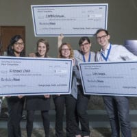 A team of ecstatic students hold up their big check prizes after winning a competition