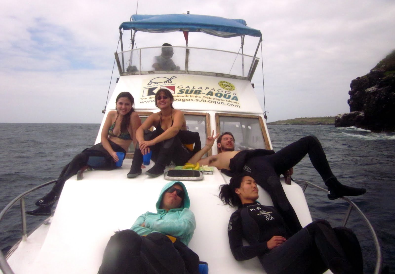 Five people sitting or lying down on a boat out in the ocean