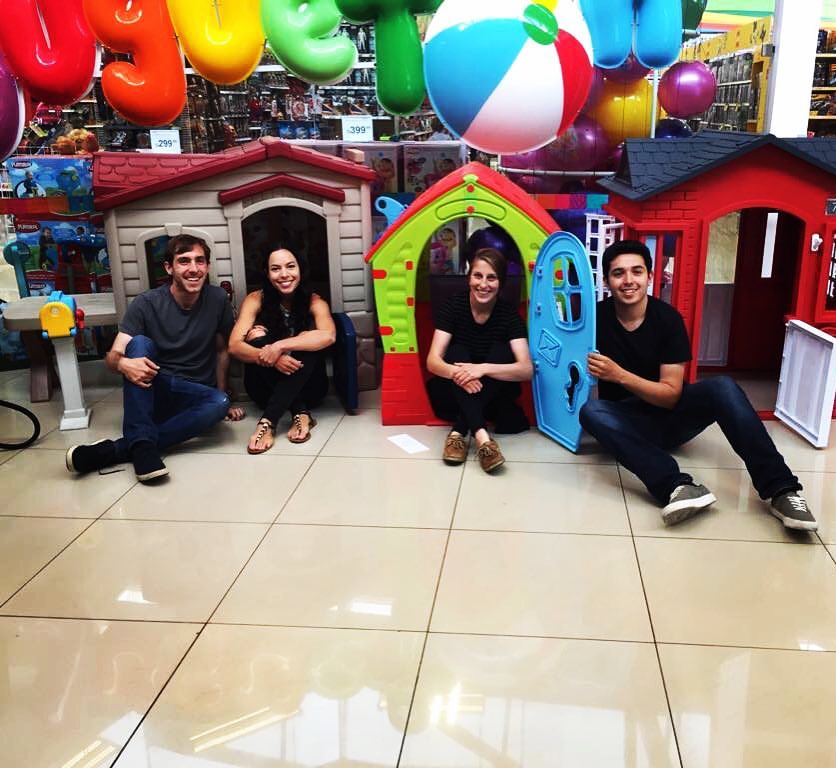 Group of adults sitting inside toy homes