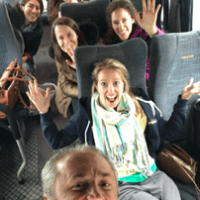 People smiling for a selfie while sitting in a bus