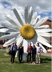 People standing in front of a large sculpture shaped like a flower