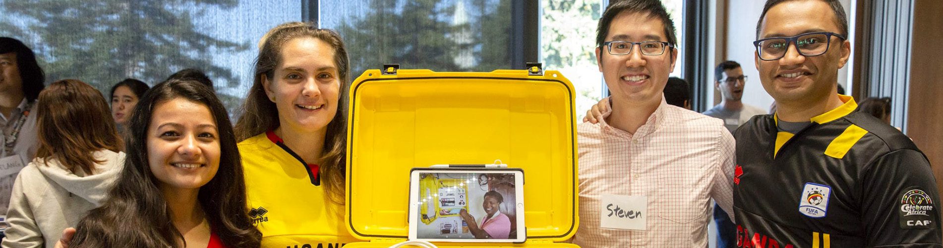 Four students with a yellow box containing a tablet with a picture of a woman